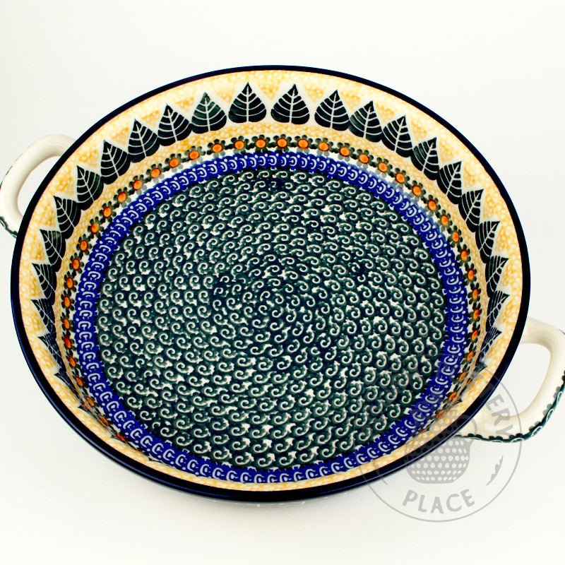 Large round polish pottery baker dish with handles and a big green leaf of with blue and yellow trim pattern