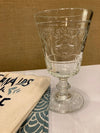 French drinking glass next to dishtowels