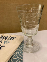 French drinking glass next to dishtowels